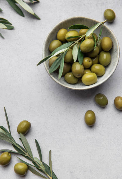 istock Green olives with leaves served in bowl on concrete table, creating mediterranean culinary scene 2198646107
