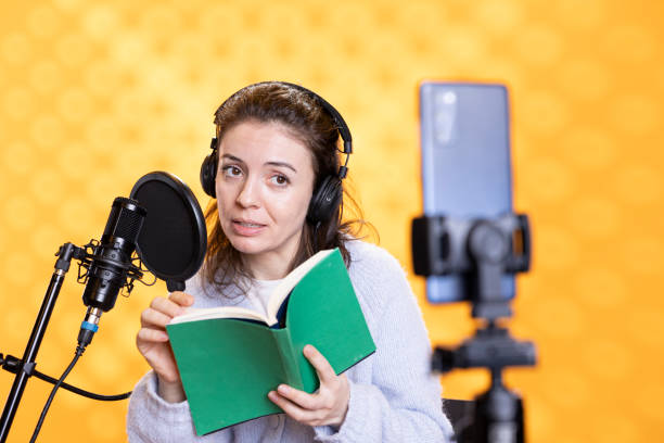 istock Influencer looks at phone camera, filming reading book, studio background 2198646489