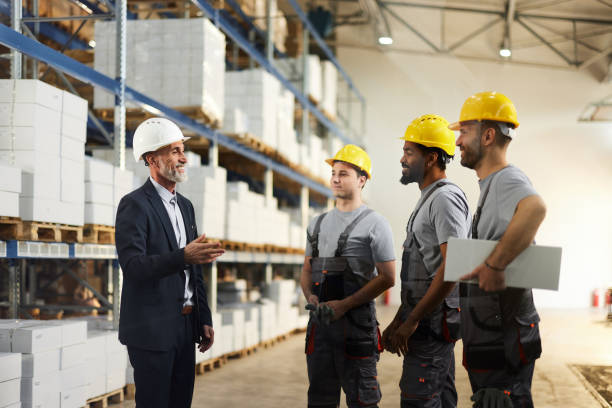 istock Happy senior inspector talking to manual workers in storage room. 2198647843