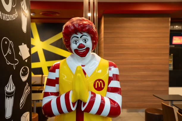 Bangkok, Thailand - October 14, 2023: life-size Ronald McDonald statue greeting customers with the traditional Thai greeting wai at McDonald's restaurant in Don Mueang International Airport.