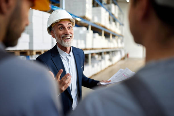 istock Happy senior inspector talking to manual workers in storage room. 2198648015