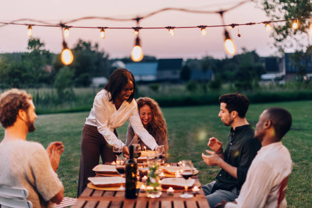 istock Friends enjoying outdoor dinner party with string lights at sunset 2198648073