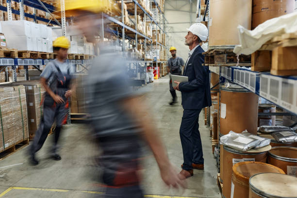 istock Pensive inspector among manual workers in blurred motion at storage room. 2198648465