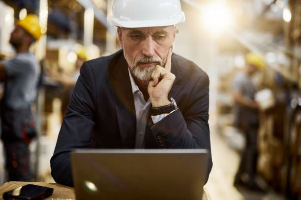 istock Thoughtful senior inspector working on laptop in storage room. 2198648832