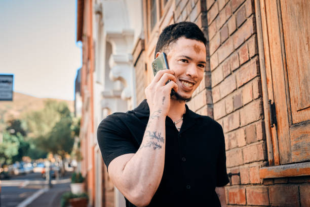 istock Stylish Young Man with Vitiligo Using Smartphone Outdoors in Urban Setting 2198650224