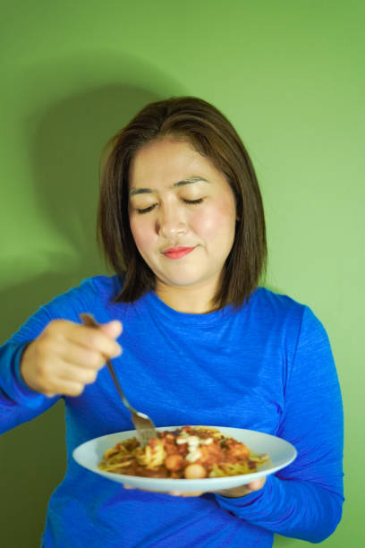 Female hands hold a fork and knife near a white plate on which the multicolored word Diet is written and a funny face is drawn.The concept of a balanced diet,ration, medical fasting.Top view, copy space.