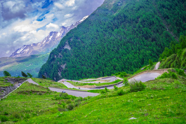 Alpine mountain road with cars driving through the hairpin corners along the Timmelsjoch high mountain pass during a beautiful springtime day in the Italian Alps of South Tirol.