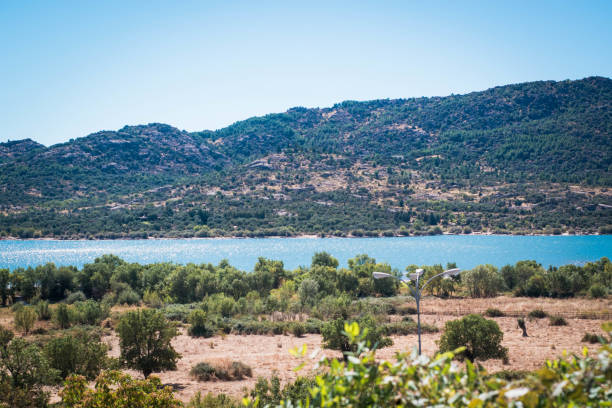 istock Serene lake surrounded by lush greenery and majestic mountains under a clear blue sky 2198658059