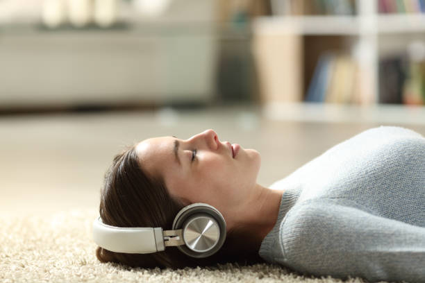 Woman with headphone lying on the floor with eyes closed listening music stock photo