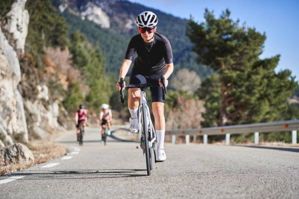 istock Focused female cyclist leading a group on a winding mountain road 2198661633