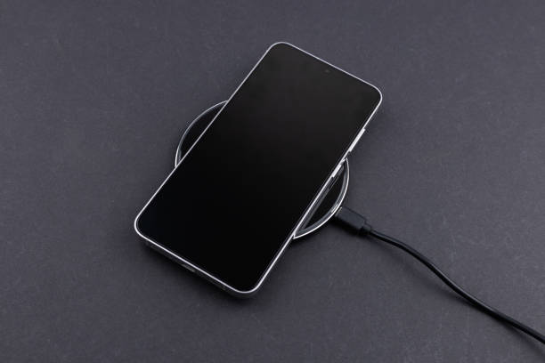 istock Mobile smart phone on wireless charging device on dark background. smartphones connected to power source 2198667372