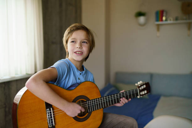istock Carefree boy playing guitar at home 2198667466