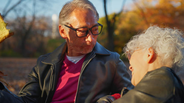 istock Senior Couple Sitting Against Tree Log with Laughter and Fun 2198669505