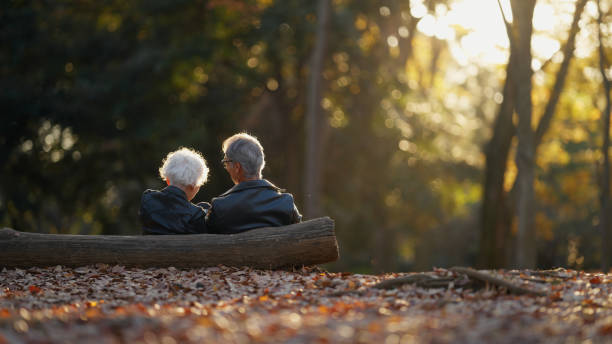 Senior Couple Sitting Against Tree Log on the Ground