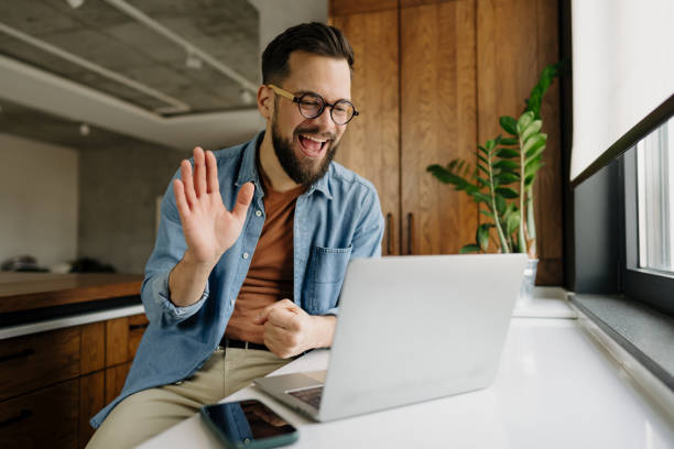istock Young man waving at someone during a video call on his laptop 2198671430