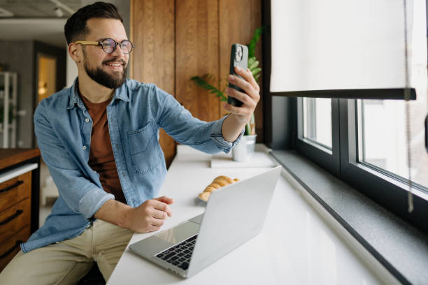 istock Young man taking a selfie with smartphone while working from home 2198671444