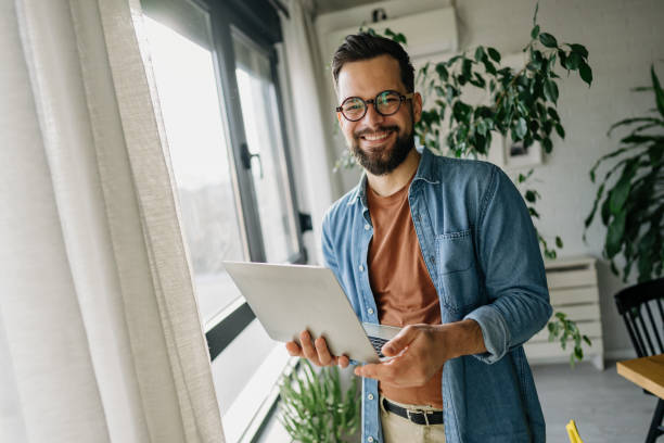 istock Young businessman smiling and holding a laptop while working from home 2198671510
