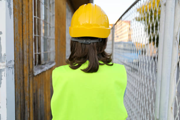 Rear view of female engineer in helmet on construction background
