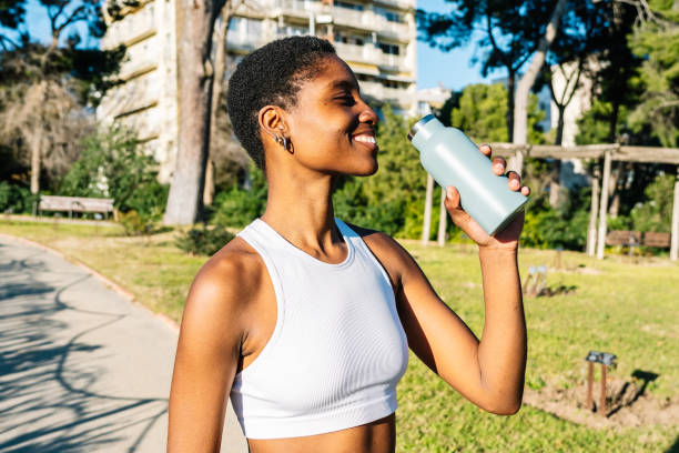istock Young black woman drinking water from reusable bottle in a park 2198680473