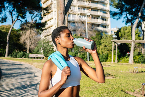 istock Young sportswoman drinking water in a park after training 2198680568