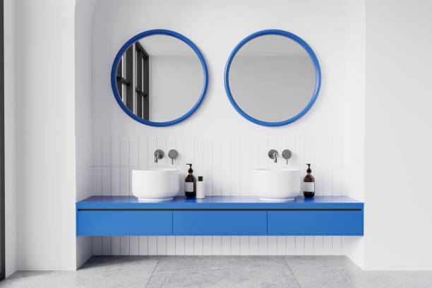 istock Modern bathroom with round mirrors and white sinks on wooden vanity against blue tiled wall. 3D Rendering 2198683352