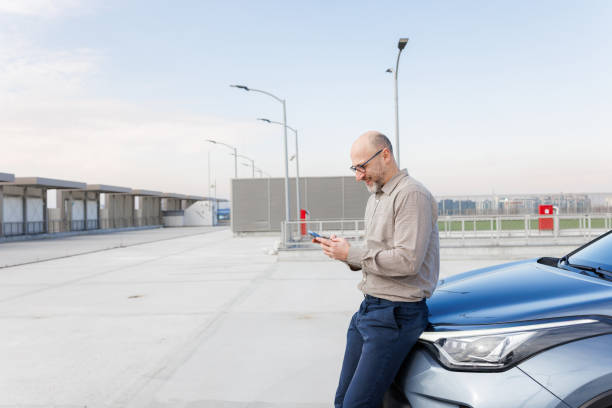 istock Casual businessman smiling while texting near his car 2198683487