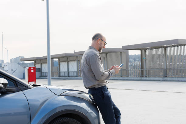 istock Mature man leaning on his car and messaging on his phone 2198683522