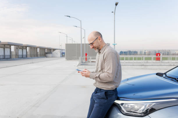 istock A man standing beside the car while engaged on smart phone 2198683525