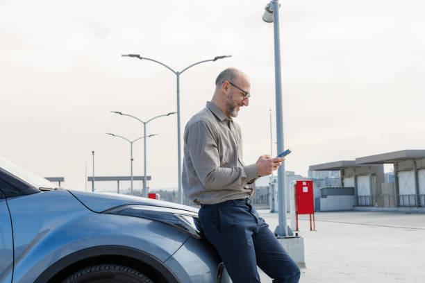 istock Casual professional standing beside car while checking phone 2198683566