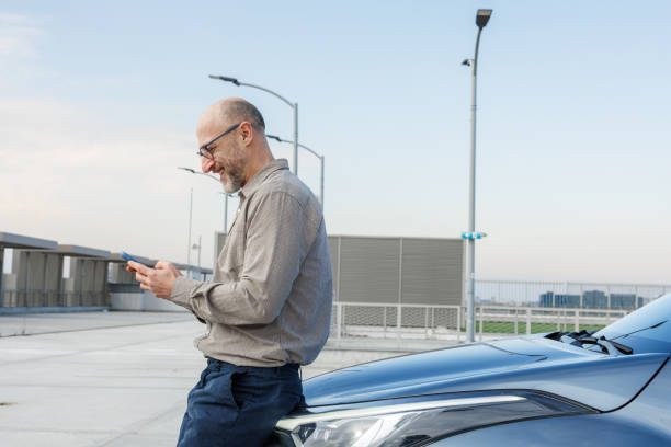 istock Relaxed mature man using smart phone near his car 2198683587