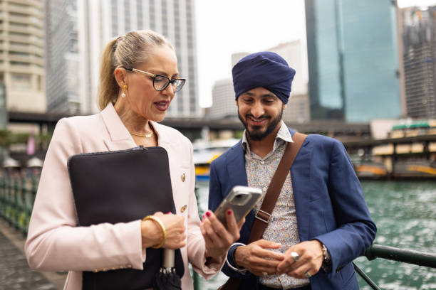 istock Two multinational professionals in business are having a conversation during their break, looking at and discussing ideas on their phone in the business district 2198686865