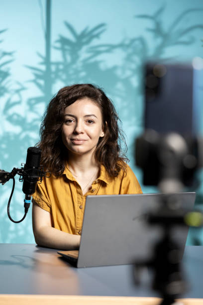 istock Smiling vlogger sitting in front of camera, reading from laptop screen 2198687178