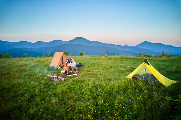 istock Two campers enjoying serene view of rolling mountains under clear sky. 2198688282