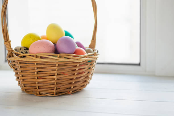 istock Wicker basket with bright colorful eggs and with text Happy Easter and flower 2198689899