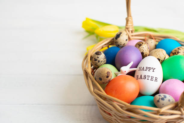 istock Wicker baskets with bright colorful eggs and with text Happy Easter and flower 2198690049