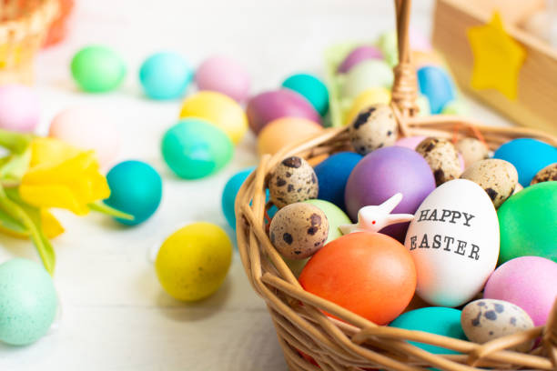 istock Wicker baskets with bright colorful eggs and with text Happy Easter and flower 2198690091
