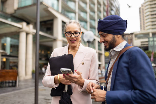 istock Two multinational business professionals talk during their break, looking at and discussing ideas on a phone in the business area 2198690723