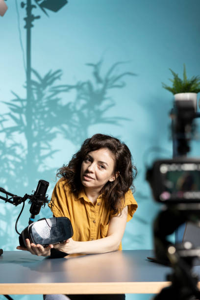 istock Smiling media star in studio presents VR goggles from brand sponsoring video 2198691680