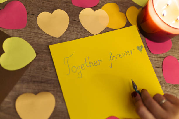istock Writing a Heartfelt 'Together Forever' Message Amidst Decorative Hearts and Candlelight 2198692101