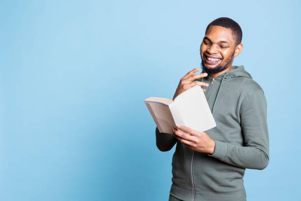 istock African american young guy engrossed in reading activity against blue background 2198693407
