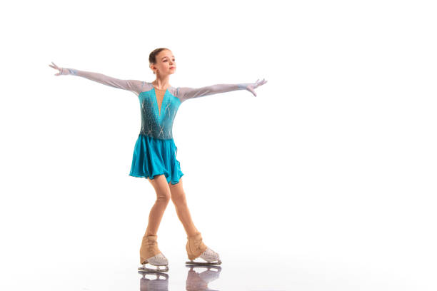 Portrait of smiling young female ballerina with arms raised jumping against white wall in studio