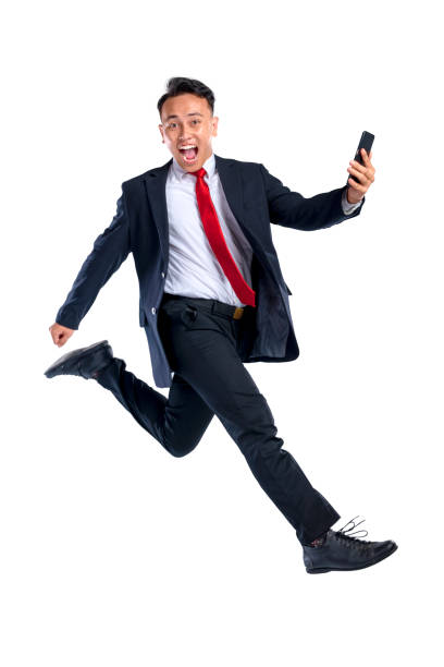 istock Portrait of an Asian businessman walking while using his mobile phone isolated over a white background. Concept of Indonesian business and technology 2198700705