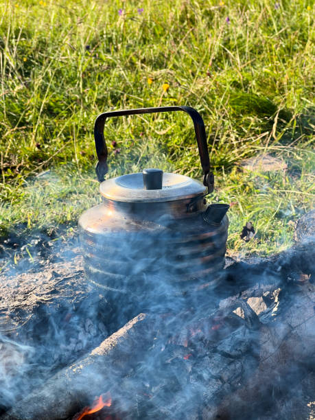 Close-up of metal kettle heating over campfire.