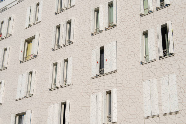 Paris,France-14.01.2025 A building features a distinct textured facade and multiple windows, some open, showcasing a modern urban aesthetic. The design highlights simplicity and elegance in construction.