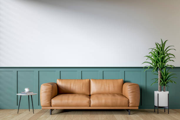 istock Modern interior: a living room with a brown leather sofa, low side table, half deep green wainscoting and half white plaster wall background and decoration 2198706068