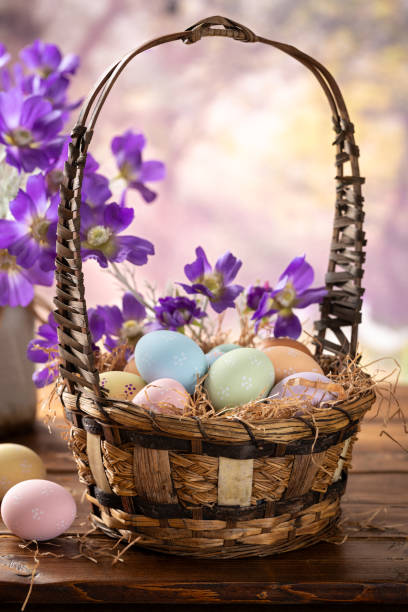 istock Easter eggs in a basket and purple daisies with vibrant spring background 2198706202