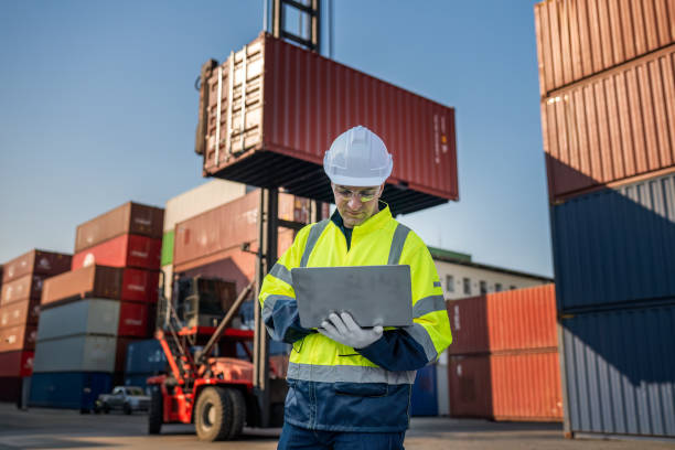istock Dock worker overseeing operations logistics and shipping yard managing inventory, shipping schedules, or container tracking technology, and safety in the shipping industry, depicting a professional in action at a container yard. 2198707587