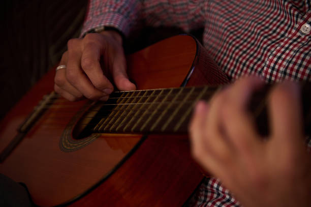 istock Hands strumming a classical guitar in a warm, intimate atmosphere 2198707610