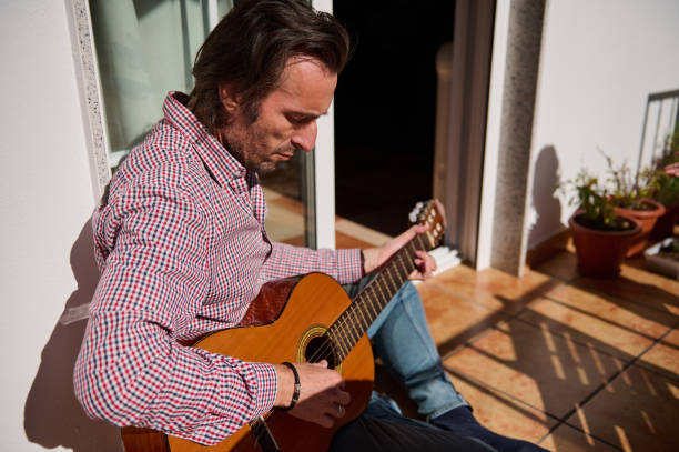 istock Man playing guitar outside on a sunny day on his patio 2198707644