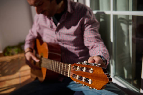 istock Person tuning a classical guitar outdoors in natural sunlight 2198707653